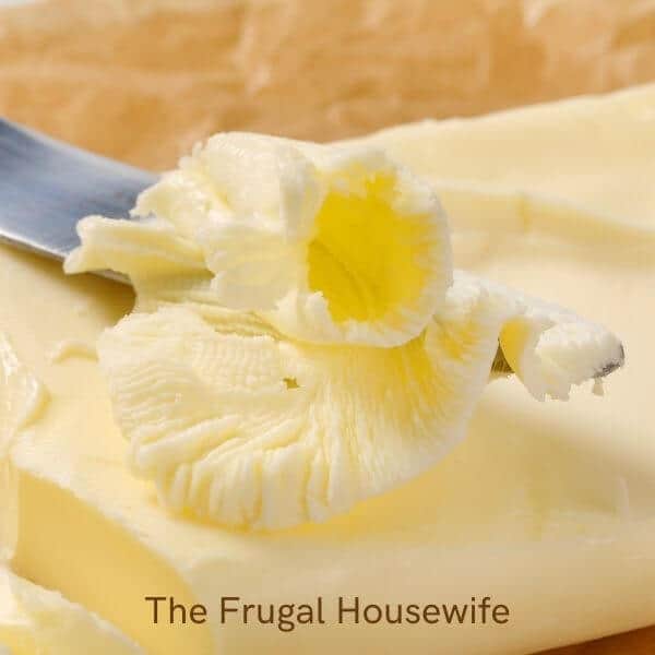 Yellow butter with knife used in the post How to Make Homemade Butter with Food Processor on The Frugal Housewife.