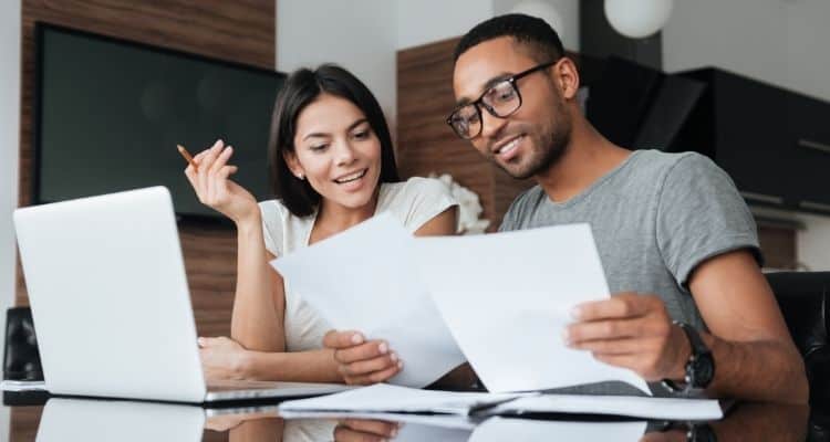 Happy couple looking at computer and financial report.
