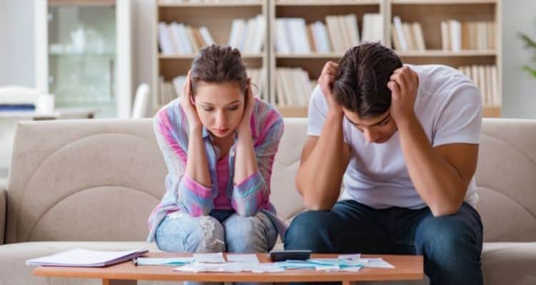 Couple looking stressed while looking at bills laying on a table.