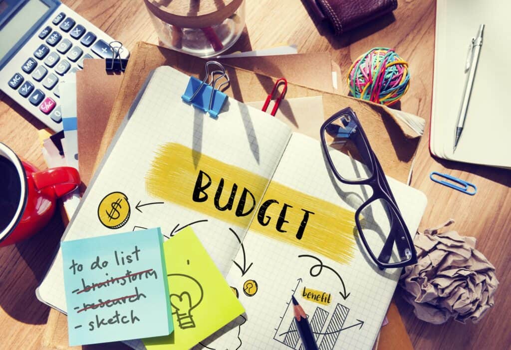 Book with the word budget laying a table with a pair of glasses.